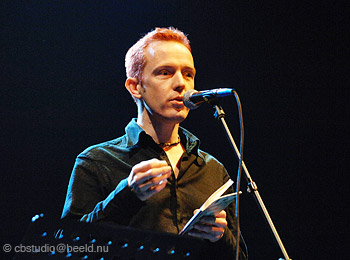 //9 foto's van Alexis de Roode achter microfoon met zwarte achtergrond en sterk afstekend rood haar, in actie tijdens voordracht//
